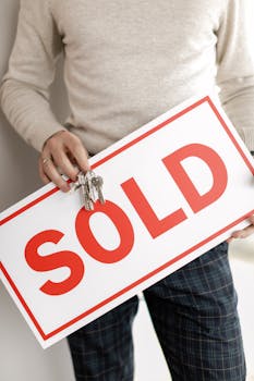 pexels-photo-7642006-7642006 Close-up of a realtor holding a sold sign and keys, symbolizing successful property sale.